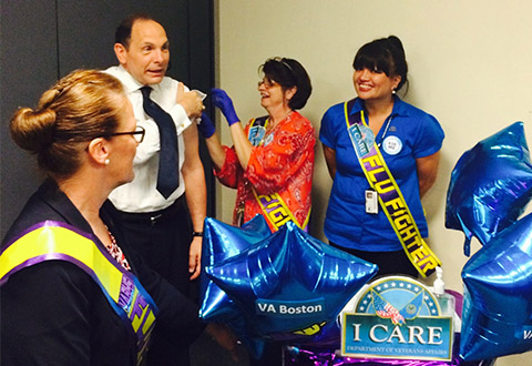 VA Secretary Bob McDonald receives a flu shot at VA Boston with staff members looking on.