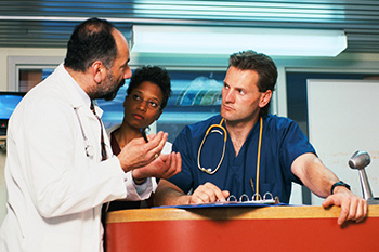Three clinicians disscussing an issue in a hospital unit.